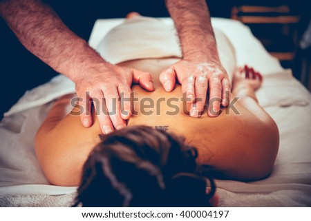 Woman enjoying relaxing back massage in cosmetology spa centre. Beauty treatment, body care, skin care, wellness, wellbeing concept. Toned picture