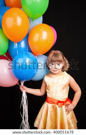 Vertical studio portrait of positive Caucasian blond little girl with colorful balloons