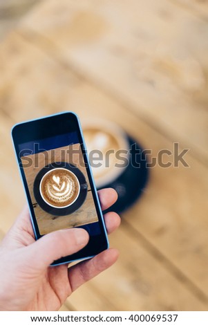 Hand Taking Picture with a Smart Phone of His Cappuccino