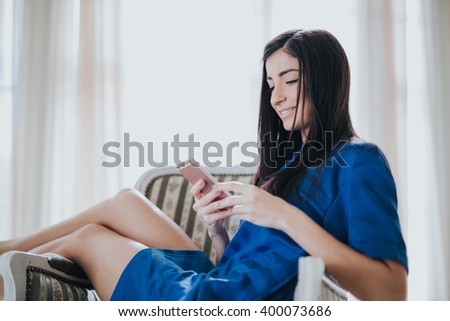 Portrait of cute teen girl texting emotional in a white bright room, spring sunny day
