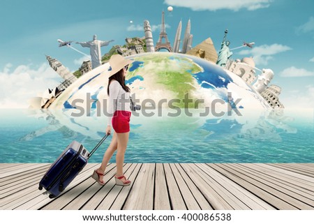 Picture of a female traveler walking on the jetty while carrying a bag, shot with the world monument background
