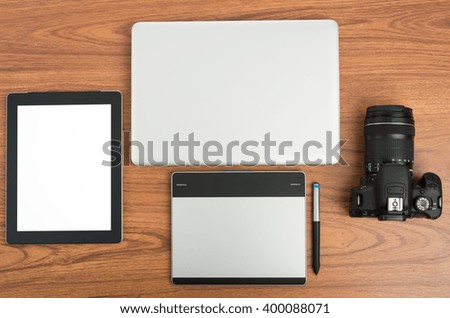 DSLR digital camera with tablet and notebook laptop on wooden desk table