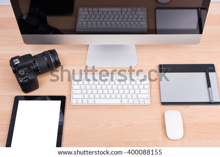 DSLR digital camera with tablet and computer PC on wooden desk table