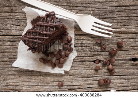 A chocolate cake or brownies with a broken plastic fork over a wooden background