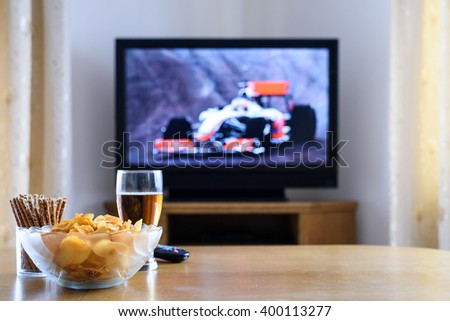 Television, TV watching (formula one race) with snacks and alcohol on table - stock photo