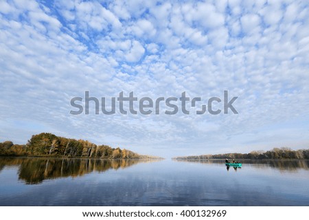 autumn landscape fisherman in an inflatable boat in the early morning on the river