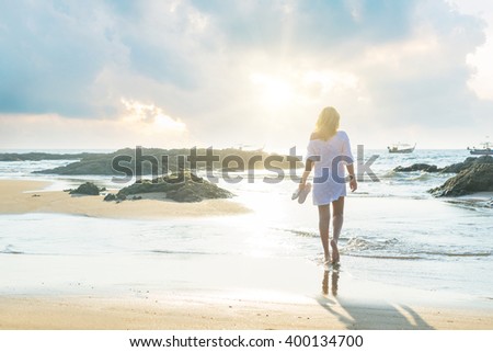 woman walking on sand beach at golden hour