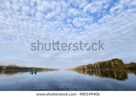 autumn landscape fisherman in an inflatable boat in the early morning on the river