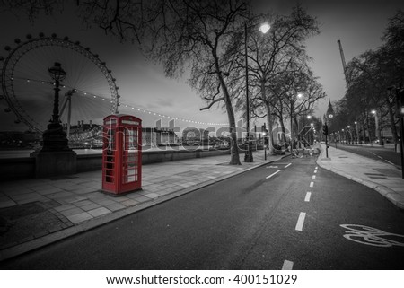 Red telephone booth isolated on black and white street