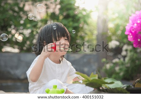 Cute asian child is blowing a soap bubbles