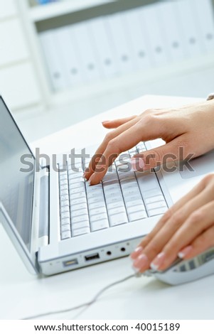 Closeup picture of female hands using laptop computer and mouse.