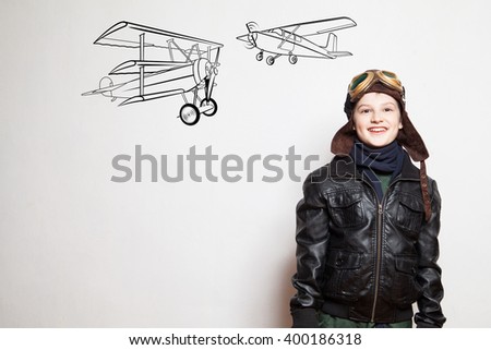 Boy pilot with drawn planes against the with. Pilot with glasses. Pilot with helmet. Pilot and draw planes.