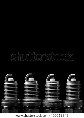 A set of new spark plugs of the car, and the spare parts of the vehicles isolated on black background. Studio macro image of high quality. To advertise auto service.
