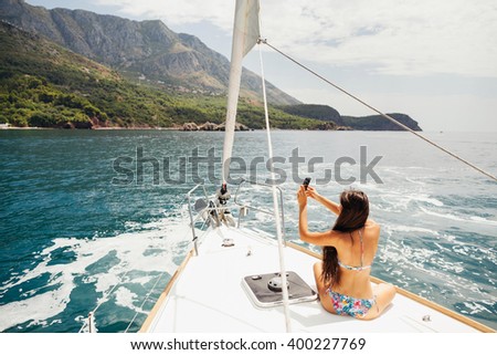 girl yachting with smartphone photograph cruise travel with picturesque seaview in Montenegro