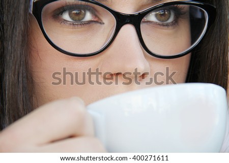Photo of the Young woman drinking coffee in a cafe outdoors