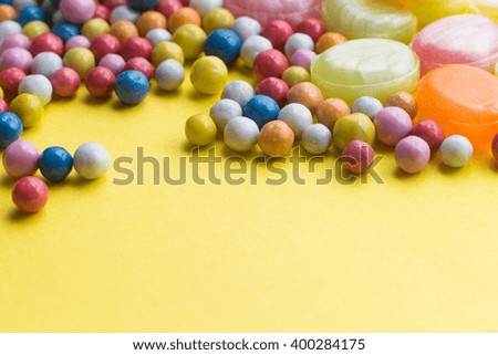 Candies colorful mix on yellow bright background with copy space.