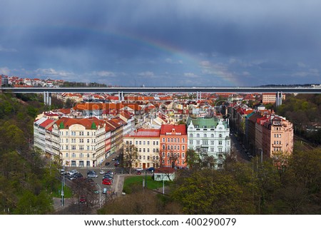 Cityscape of Prague, aerial view of prague taken from vysehrad castle complex captures detail of typical red rooftops  under Nusle Bridge and rainbow