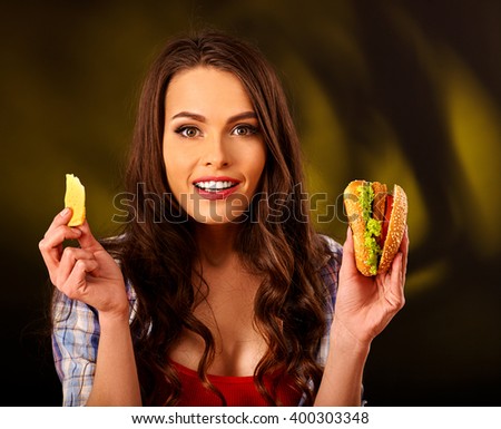 Portrait of girl with long hair holding  small hamburgers. Fastfood concept on green.