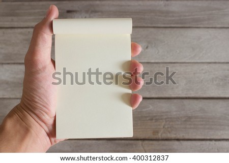 notebook in hand with wood background