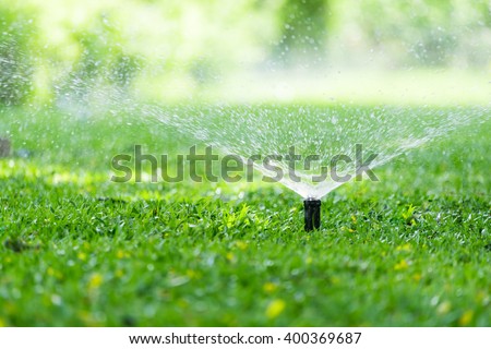 Automatic Garden Lawn sprinkler in action watering grass. Royalty-Free Stock Photo #400369687