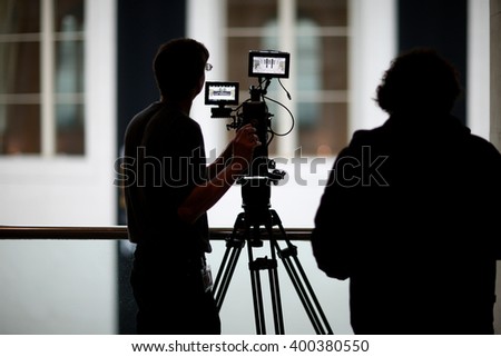 Silhouettes of professional operator taking video  Royalty-Free Stock Photo #400380550