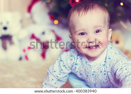 Cute little baby boy smiling portrait on blurred Christmas background with gifts and Christmas tree. Vintage style toned image