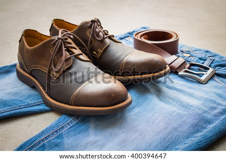 Men's casual outfits with blue jeans, belt and brown shoes on gray background