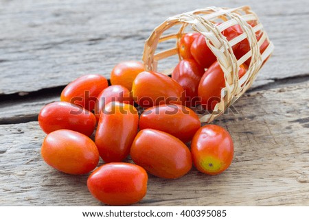 Fresh tomatoes with basket on wood
