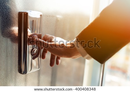 Man pressing elevator button. finger presses the elevator button. Red button. sunset light. businessman is a lift. high floor. hand reaches for the button of the elevator call.