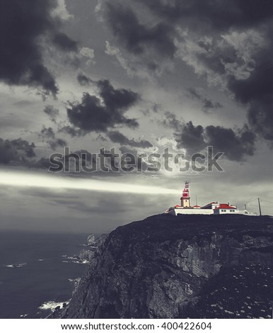Lighthouse of  Cabo da Roca cape at night . Portugal . Monochromatic picture with colored lighthouse. Travel and business concept