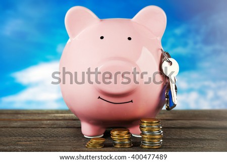 Piggy bank style money box on wooden table, sky background