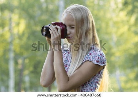 Young beautiful girl photographer. The girl with the camera has been shooting in the woods