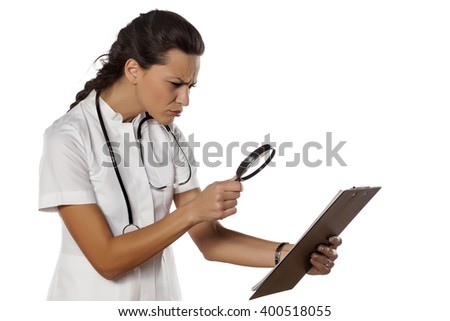a young woman doctor reading her clipboard with a magnifying glass