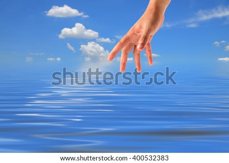 Grab the hand on sky-clouds and sea background.