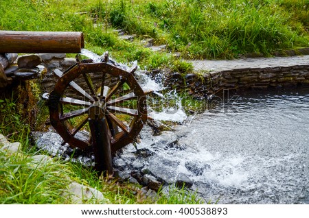 Working watermill wheel with falling water in the village Royalty-Free Stock Photo #400538893