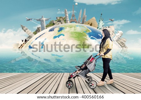 Picture of a young woman carrying her baby on the stroller with the world monument background