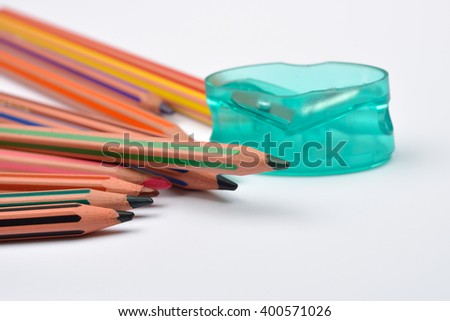 Picture of some pencils with stripes of different colors and pencil sharpener on a white background. Selective focus