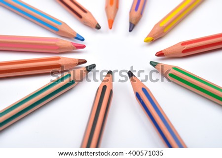 Close up picture of colored pencil crayons with stripes arranged in circle on white background. Assortment of colored pencils/ Colored drawing pencils. Selective focus