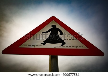 A pedestrian crossing sign featuring a robed figure.