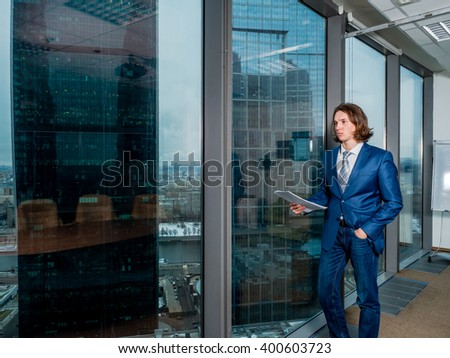 Businessman standing in an office near the panoramic windows with views of Moscow