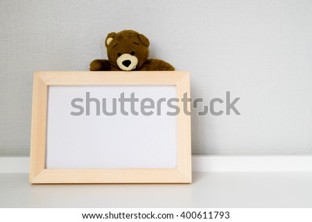 The white shelf decoration by wooden picture frame and teddy bear; close up 