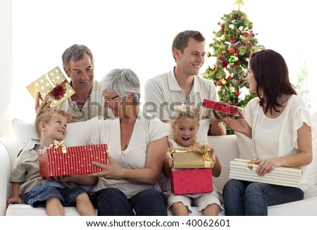 Happy family at home sitting on sofa opening Christmas presents