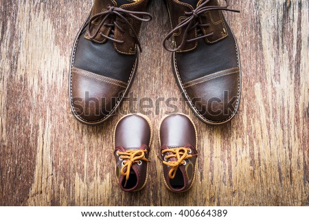 Father and son brown shoes on wooden background, fathers day  Royalty-Free Stock Photo #400664389