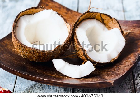 Fresh coconuts in the shell in a wooden bowl on a blue background, tropical fruit Royalty-Free Stock Photo #400675069