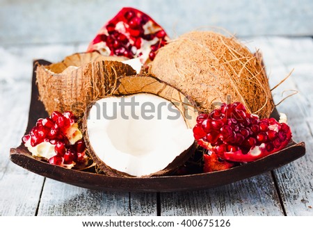 Fresh coconut and red garnet in a wooden bowl,blue background, tropical fruit