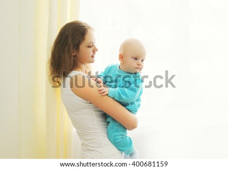 Happy mother with her baby at home near window
