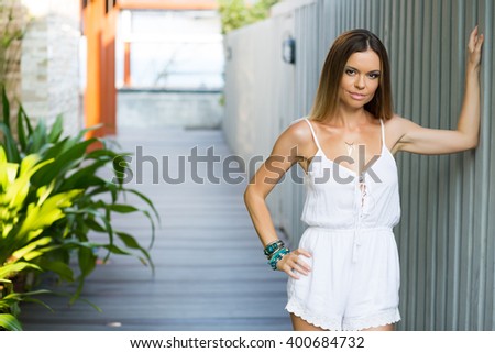 simple photo of young beautiful woman in white clothes, standing in a street, sunset light, trees