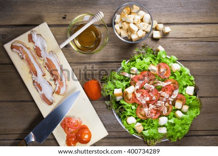 Salad with bacon, olives and tomatoes on wooden table. Top view