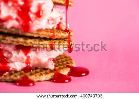 Macro of vanilla ice cream and waffles poured with berry sirup. Pink background