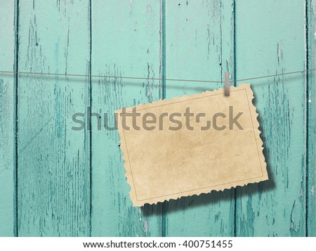 Close-up of one blank brown vintage postcard frame hanged by peg against aqua wooden background